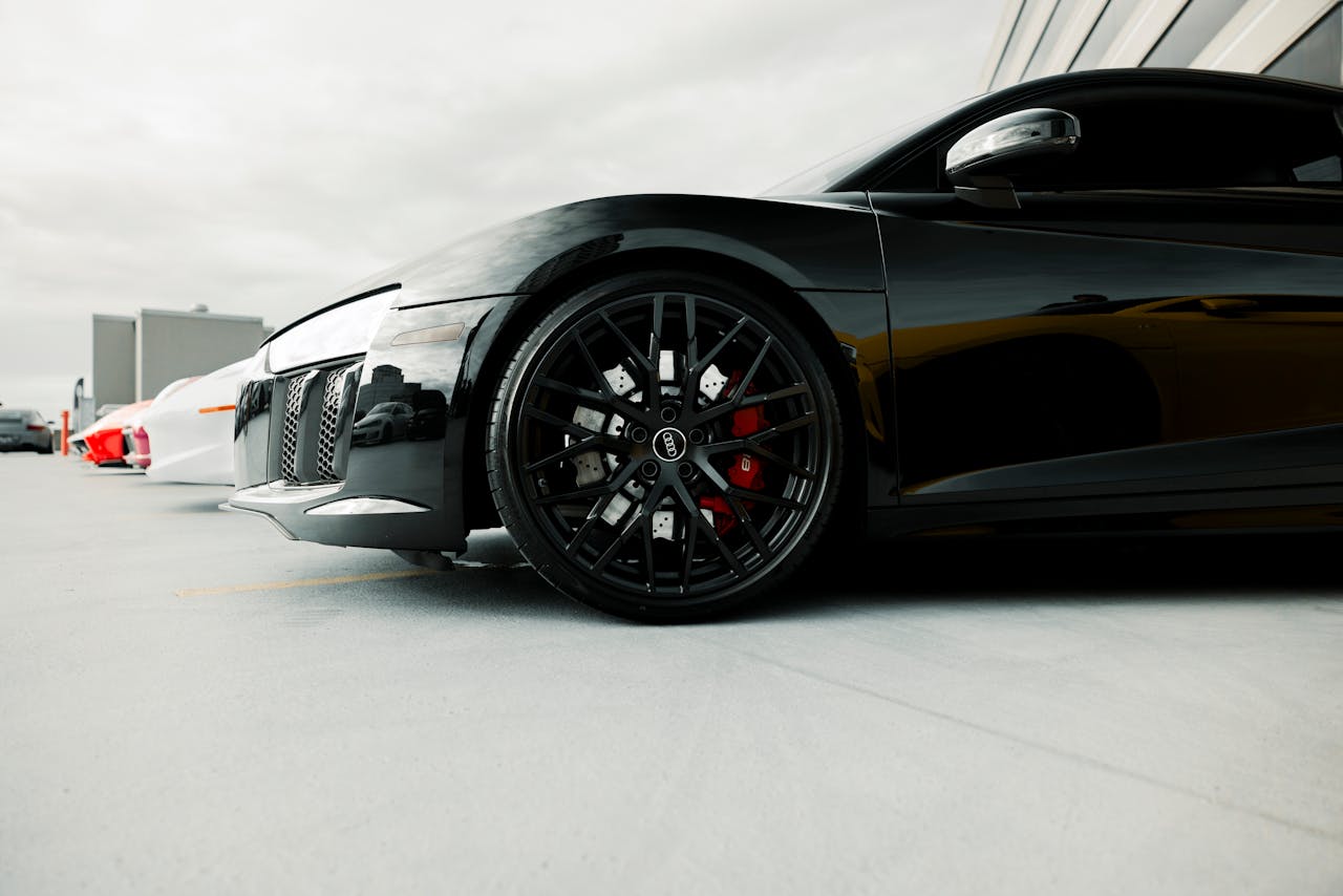 Close-up of a black luxury sports car's wheel detail in an outdoor setting.